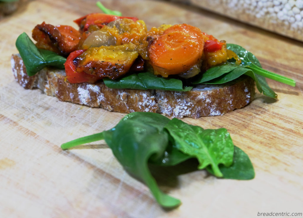 A sandwich with spinach and roasted vegetables