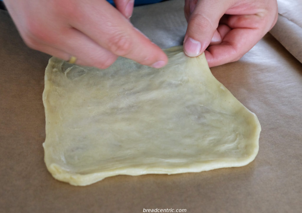 Spreading the dough, as mentioned, pressing against the paper gives better results than stretching in the air